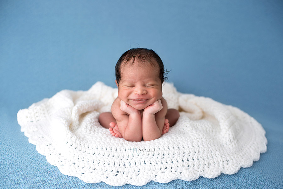 newborn smiling in head in hands froggy pose chicago il