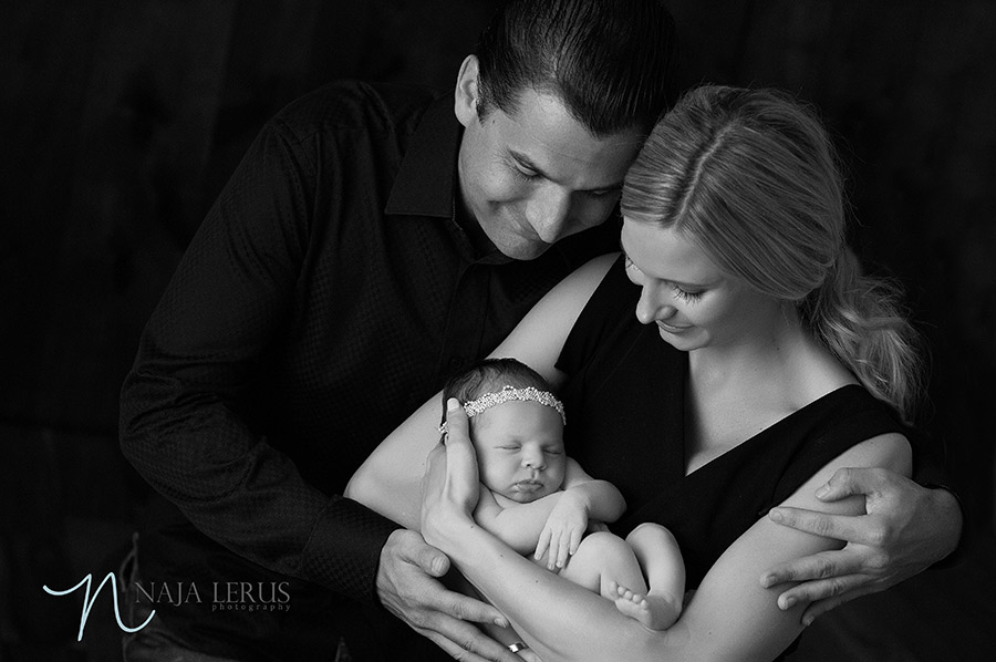 Black and white image parents posing with new baby